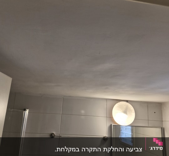 תקרה וקיר בחדר אמבטיה עם מראה ותאורה
